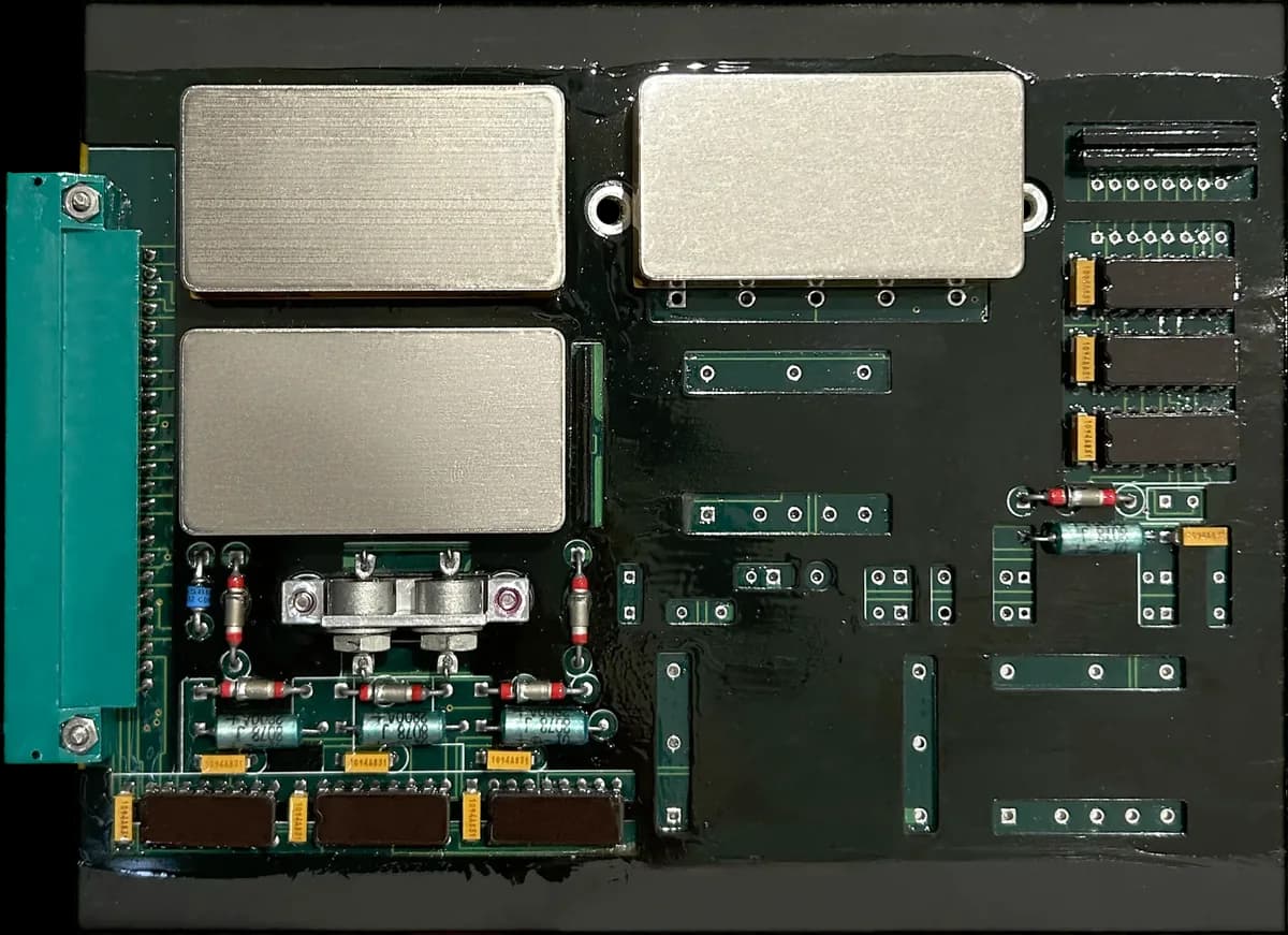 A black flight-control board with three metal shields and an edge connector